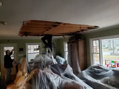 Crew working at an opened ceiling above plastic-covered furniture after an Oak Ridge roof leak