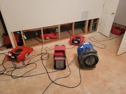 Kernersville room with the lower drywall cut out, red air movers and a dehumidifier drying the wall cavities