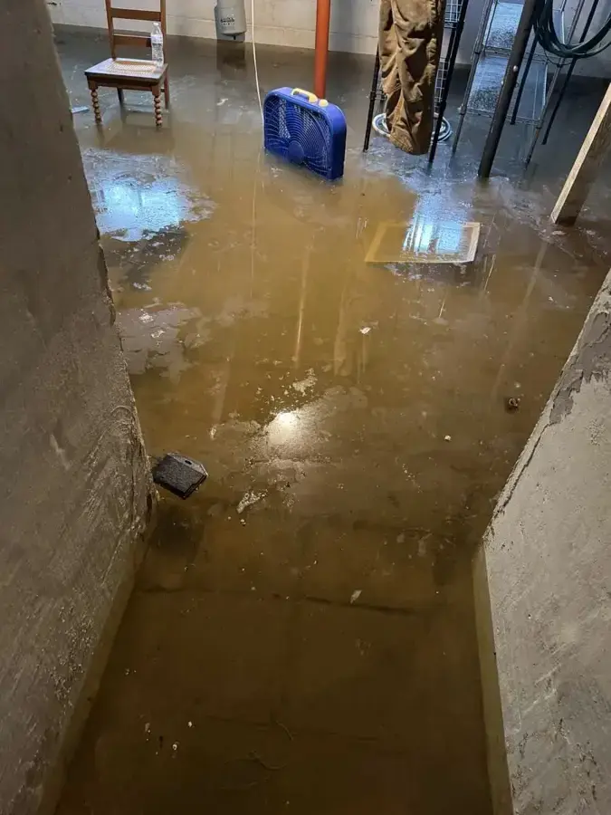 Muddy storm water covering a basement floor at the foot of the stairs in Kernersville